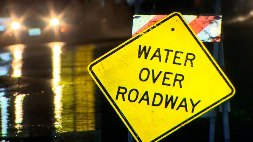 Street with yellow "Water Over Roadway" sign