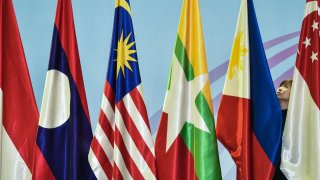 A woman (R) adjusts the Philippines flag before the 51st Association of Southeast Asian Nations (ASEAN)- Republic of Korea Ministerial Meeting in Singapore on August 3, 2018.