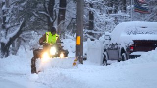 A man plows a snow covered driveway,.