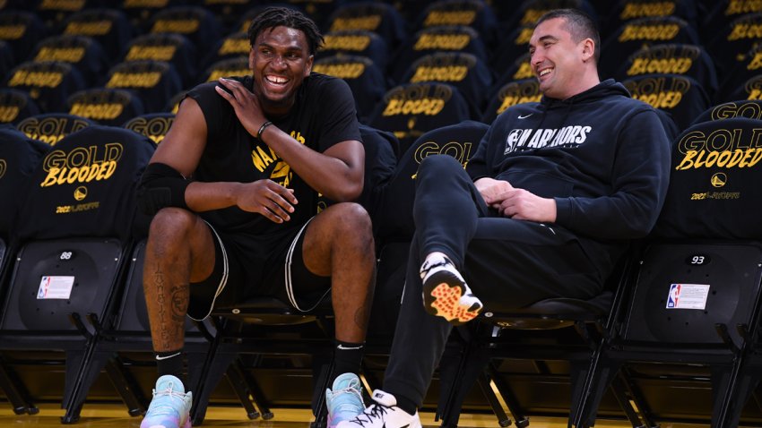 Warriors center Kevon Looney talks to assistant coach Dejan Milojević before a game on April 16, 2022.