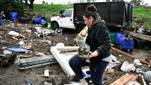 Marlene Sanchez-Barriento salavages items behind her home damaged by flooding, Tuesday, Jan. 23, 2024, in. Sanchez-Barriento's home was damaged when flood waters rushed though her home on Monday, Jan. 23. (AP Photo/Denis Poroy)