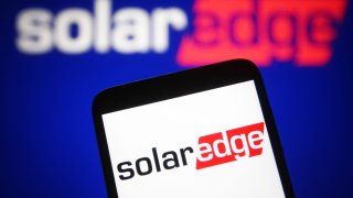 A SolarEdge Technologies logo is seen on a smartphone and a PC.