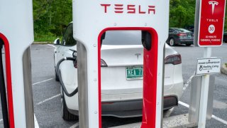 A Tesla electric car is plugged into a recharging terminal at a Healthy Living Market store in South Burlington, Vermont, June 18, 2023.