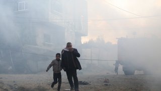 Palestinians run away after an Israeli strike on a residential building