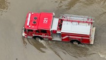 A fire truck driving through flooding in San Diego
