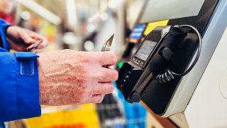 Close up of man making contactless card payment at the self-service checkout