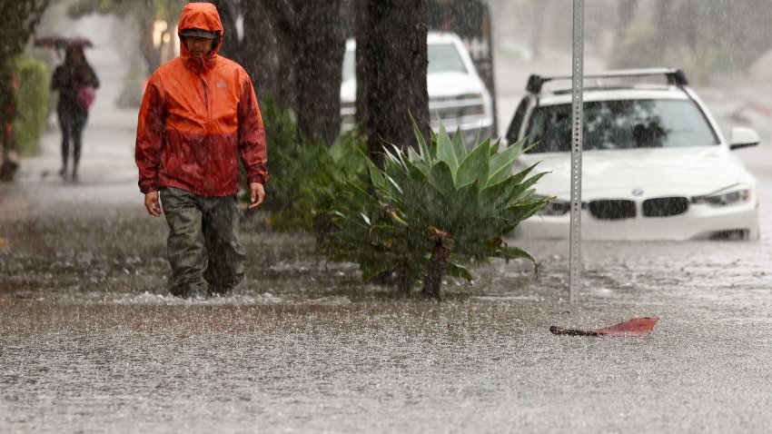 A person walks along a flooded street.