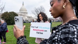FILE - Devotees of TikTok, Mona Swain, center, and her sister, Rachel Swain, right, both of Atlanta, pose with a sign at the Capitol