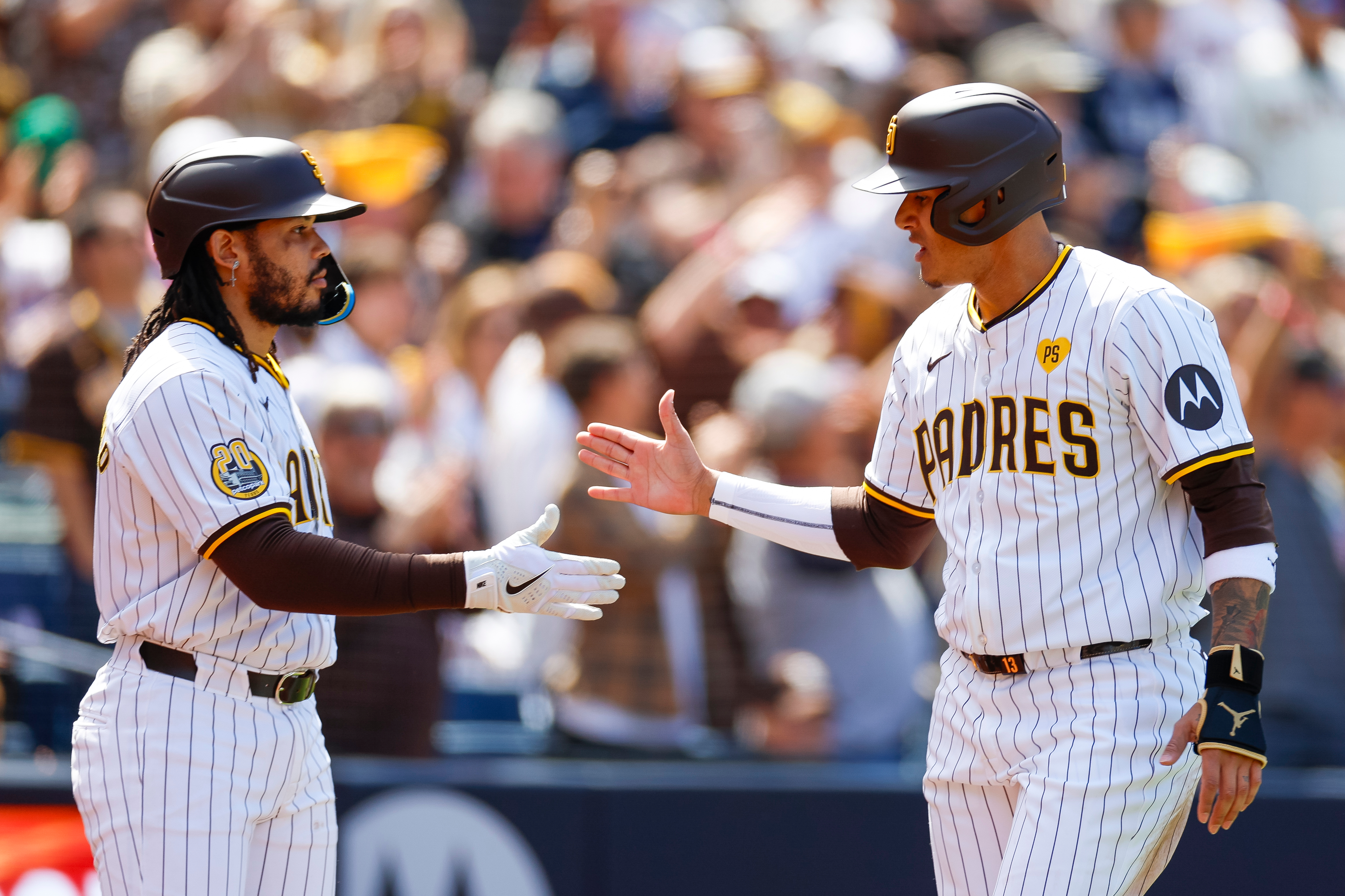 Manny Machado high-fives Luis Campusano of the San Diego Padres after scoring on a single by Jurickson Profar in the fifth inning during an Opening Day game against the San Francisco Giants at Petco Park on March 28, 2024.