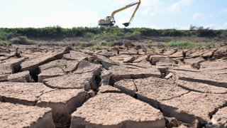 An excavator drives past a dried-up pond in Vietnam’s southern Ben Tre province on March 19, 2024. 