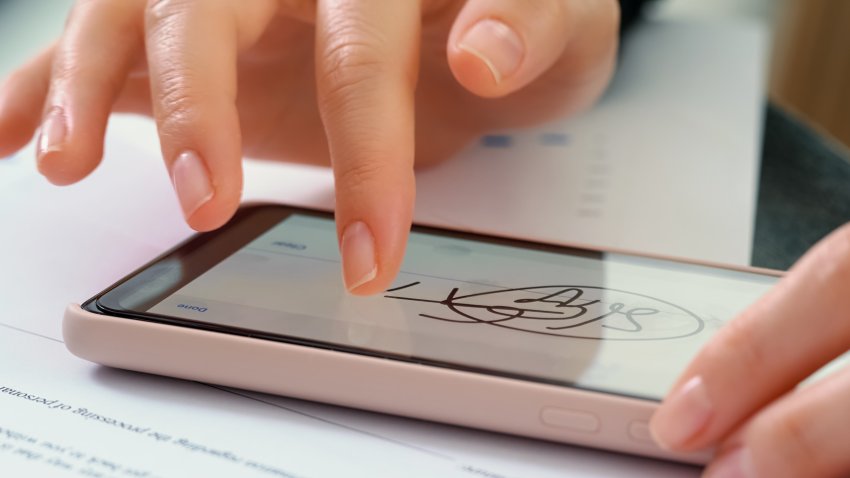 Electronic Signature on smartphone screen with woman hand. Sign Document of Deal at Work in Office Indoors. Write Business Agreement for Entrepreneur. Contract digital signature.