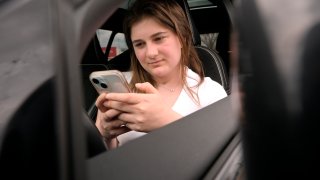 Alexis Bogan, whose speech was impaired by a brain tumor, uses an AI powered smartphone app to create a audible drink order at a Starbucks drive-thru on Monday, April 29, 2024, in Lincoln, R.I. The app converts her typed entries into a verbal message created using her original voice.