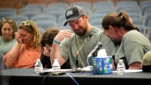 James Herling pauses his testimony while recalling the moment he realized the shooter was his brother-in-law, Robert Card, while testifying, Thursday, May 16, 2024, in Augusta, Maine, during a hearing of the independent commission investigating the law enforcement response to the mass shooting in Lewiston, Maine. Nicole Herling, sister of the shooter, cries on her husband's shoulder. 