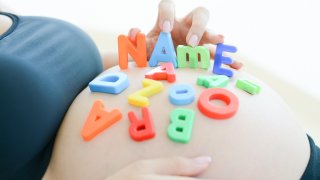expectant mother spelling name on her pregnant belly