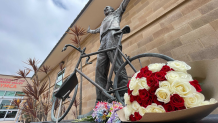 Flowers left outside of the Mission Valley YMCA on May 27, 2024. There is a statue of Bill Walton with his bike and a plaque that reads, “The Y saved my life.”