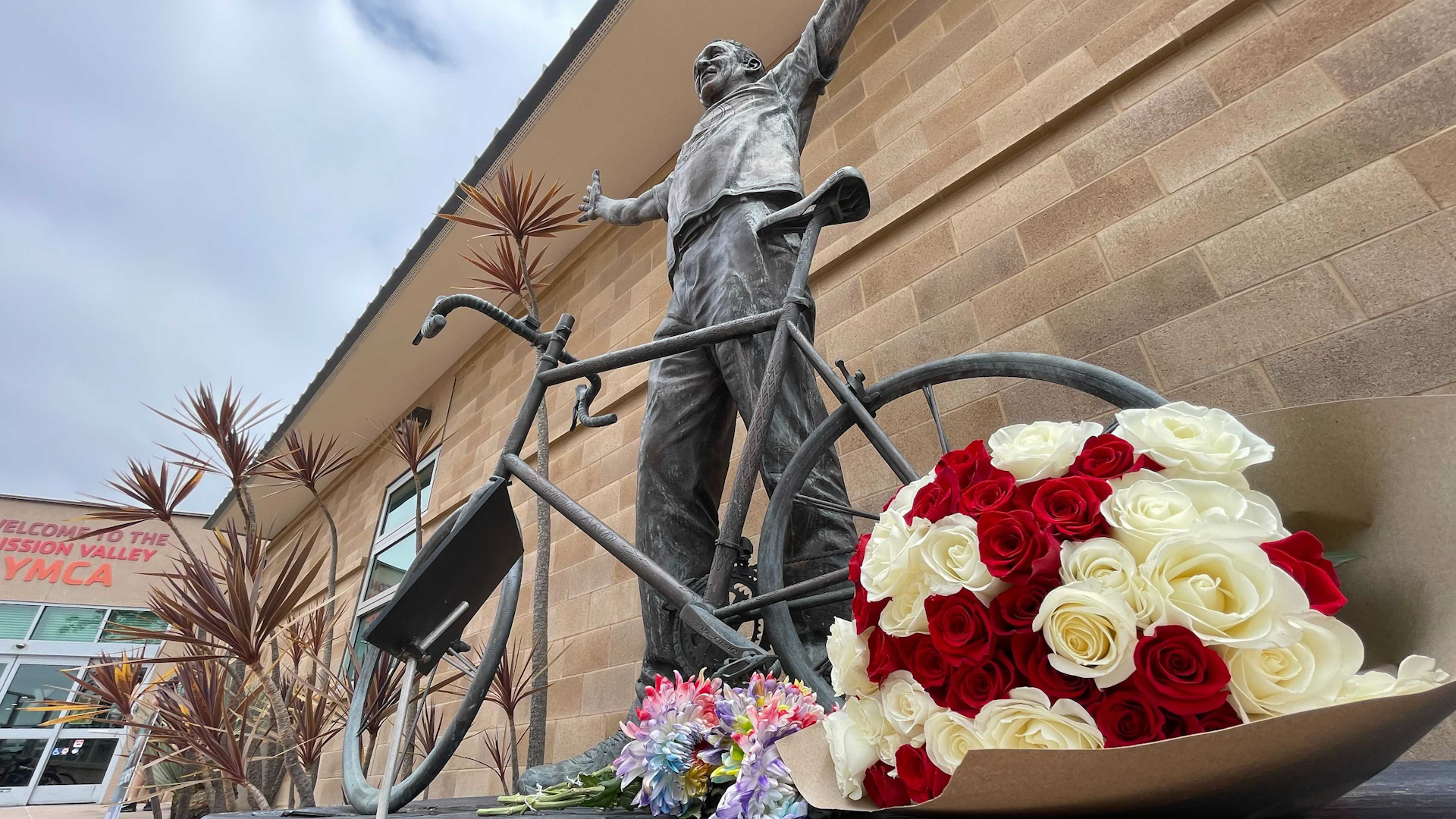 Flowers were laid outside the Mission Valley YMCA on May 27, 2024. There is a statue of Bill Walton on his bike and a plaque that reads, 