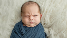 A baby making a face at the camera.