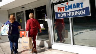 A Now Hiring sign hangs near the entrance to the PetSmart store on December 03, 2021 in Miami, Florida.