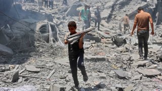 A boy carries salvaged items from the rubble of a building destroyed during Israeli bombardment at al-Shati refugee camp in Gaza City on June 22, 2024, amid the ongoing conflict between Israel and Palestinian militant group Hamas.