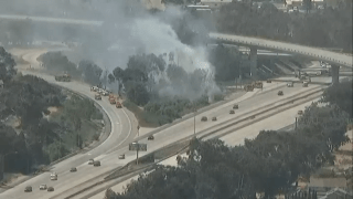 Fire crews work to put out a brush fire near the I-805 near Palm Ave, June 18, 2024.