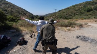 A Border Patrol agent checks a migrant seeking asylum before the man is transported and processed, Wednesday, June 5, 2024, near Dulzura, Calif.