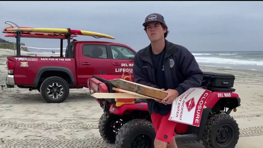 Beach closure signs come down in Del Mar after a shark attack on Saturday.