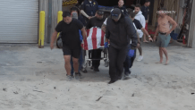 Loved ones carry the body of a Oakland firefighter who dronwned in San Diego's Pacific Beach on June 27.