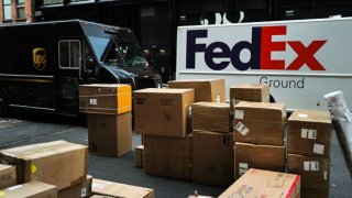 Parcels are seen in a street nearby UPS and FedEx trucks in a street of the Manhattan borough in New York City on December 4, 2023. 