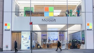 People walk past a Microsoft store entrance with the company’s logo on top in midtown Manhattan at the 5th avenue in New York City, U.S. (Photo by Nicolas Economou/NurPhoto via Getty Images)