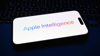 In this photo illustration, a mobile phone screen in front of a computer screen displays the Apple Intelligence logo in Ankara, Turkey, on June 10, 2024.