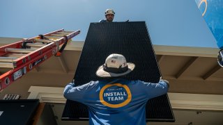 Workers install solar panels during a SunPower installation on a home in Napa, California, on July 17, 2023.