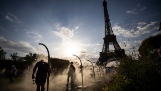 People cool off themselves with water sprays besides the Eiffel Tower in Paris on July 29, 2024, during the Paris 2024 Olympic Games.