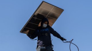 A contractor carries a SunRun solar panel on the roof of a home in San Jose, California, U.S., on Monday, Feb. 7, 2022. 