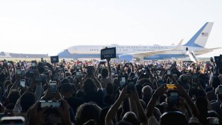 People cheer and hold signs at a campaign rally for Vice President Kamala Harris and her running mate, Tim Walz, in Romulus, MI, on August 7, 2024.