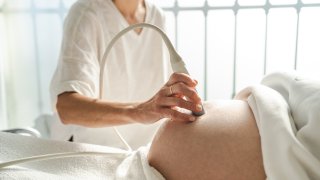 Doctor performing an ultrasound scan to the belly of a pregnant woman