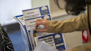 An attendee takes information about a California State job at a City Career Fair hiring event in Sacramento, California, on June 5, 2024.