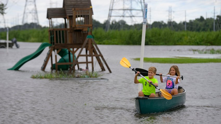 Siblings Avery, 10, and Grace LeBlanc, 7, canoe in their backyard next to playground equipment