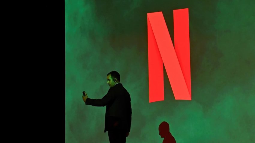 A man is seen taking a photo near the Netflix logo inside a studio hall in Mumbai. 