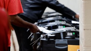 Voters place their ballot in the tabulator as they cast their in-person early ballot for the 2024 general election at the Northwest Activities Center on October 29, 2024 in Detroit, Michigan. 