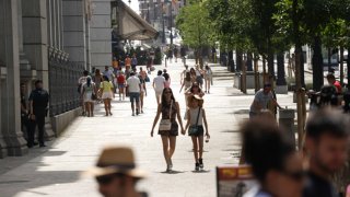 People walk down the iconic Alcalá street on a very hot afternoon in Madrid, Spain.