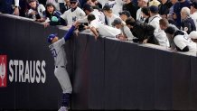 Fans interfere with a foul ball caught by Los Angeles Dodgers right fielder Mookie Betts during the first inning in Game 4 of the baseball World Series against the New York Yankees, Tuesday, Oct. 29, 2024, in New York. (AP Photo/Ashley Landis)