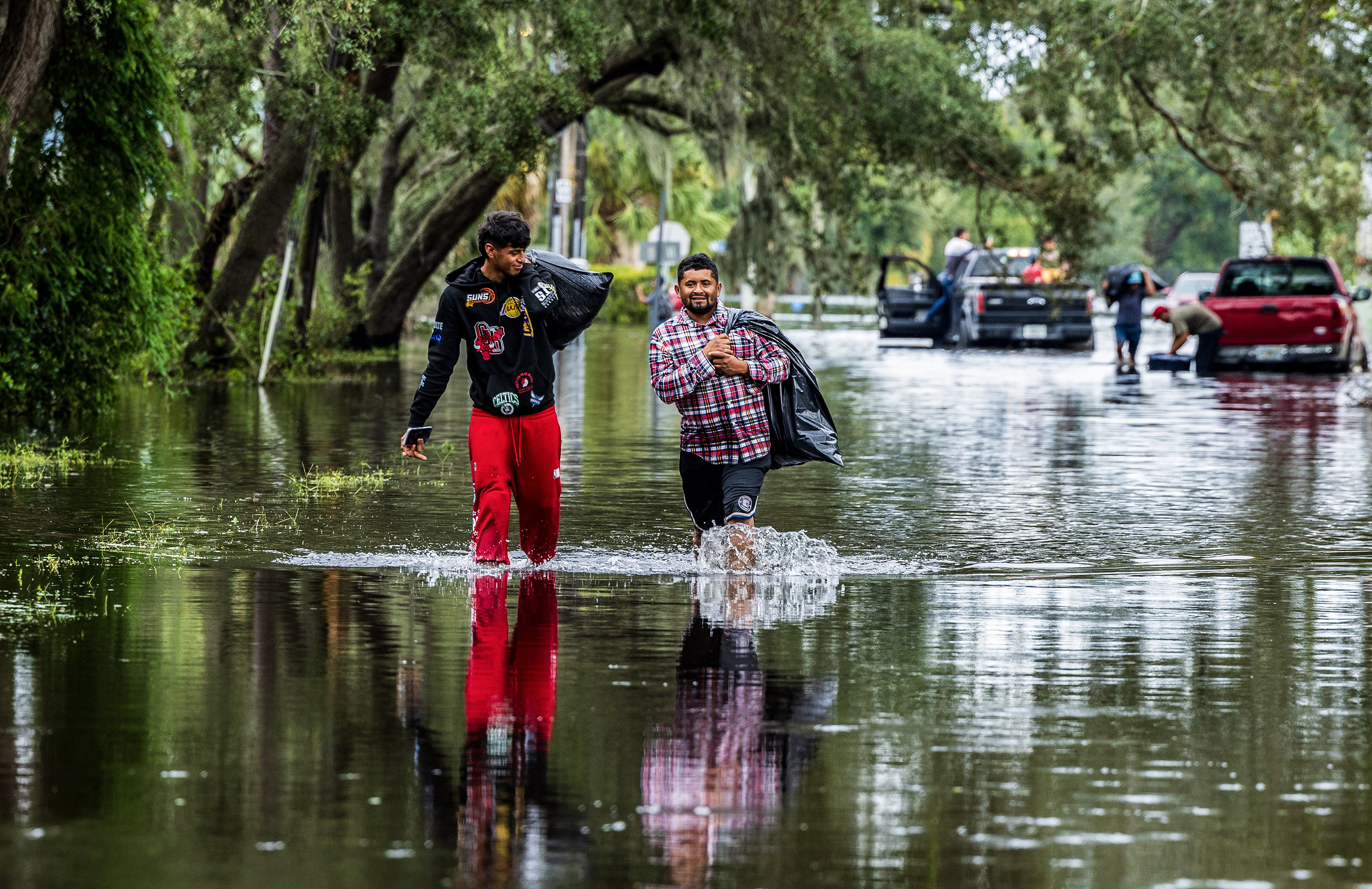 Juan Jose Muñoz (left) and Elvin Antonio Urbina (right) walk with her belongings through the flooded street in North Tampa, Florida, Thursday, Oct. 10, 2024.