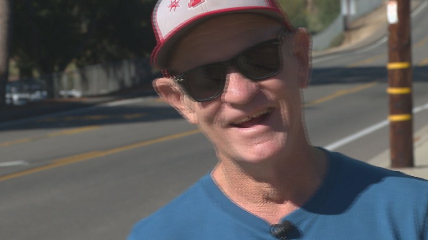 Man smiles while wearing a red and white hat and blue shirt.