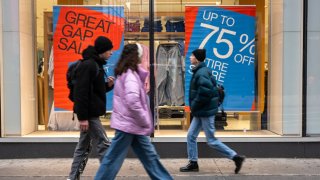 People walk by sale signs in the Financial District on the first day back for the New York Stock Exchange (NYSE) since the Christmas holiday on December 26, 2023 in New York City.