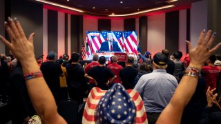 Attendees cheer as a broadcast of former US President and Republican presidential candidate Donald Trum speaking at his Florida election party is shown on a screen at the Nevada GOP election watch party in Las Vegas, Nevada on November 6, 2024.