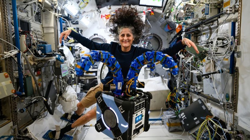 Suni Williams checks out the Astrobee robotic free-flyer on the International Space Station on Nov. 15. The device is outfitted with tentacle-like arms containing gecko-like adhesive pads to demonstrate satellite capture techniques.