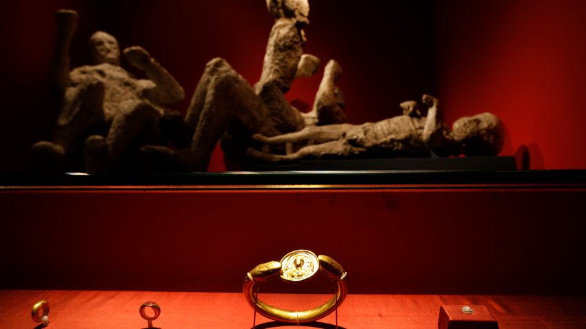 FILE – Jewelry found in the ruins of a house in Pompeii are displayed, backdropped by the casts of two adults and two children who died together in the house in Pompeii, at the exhibition, “Life and death Pompeii and Herculaneum,” at the British Museum in central London, March 26, 2013.