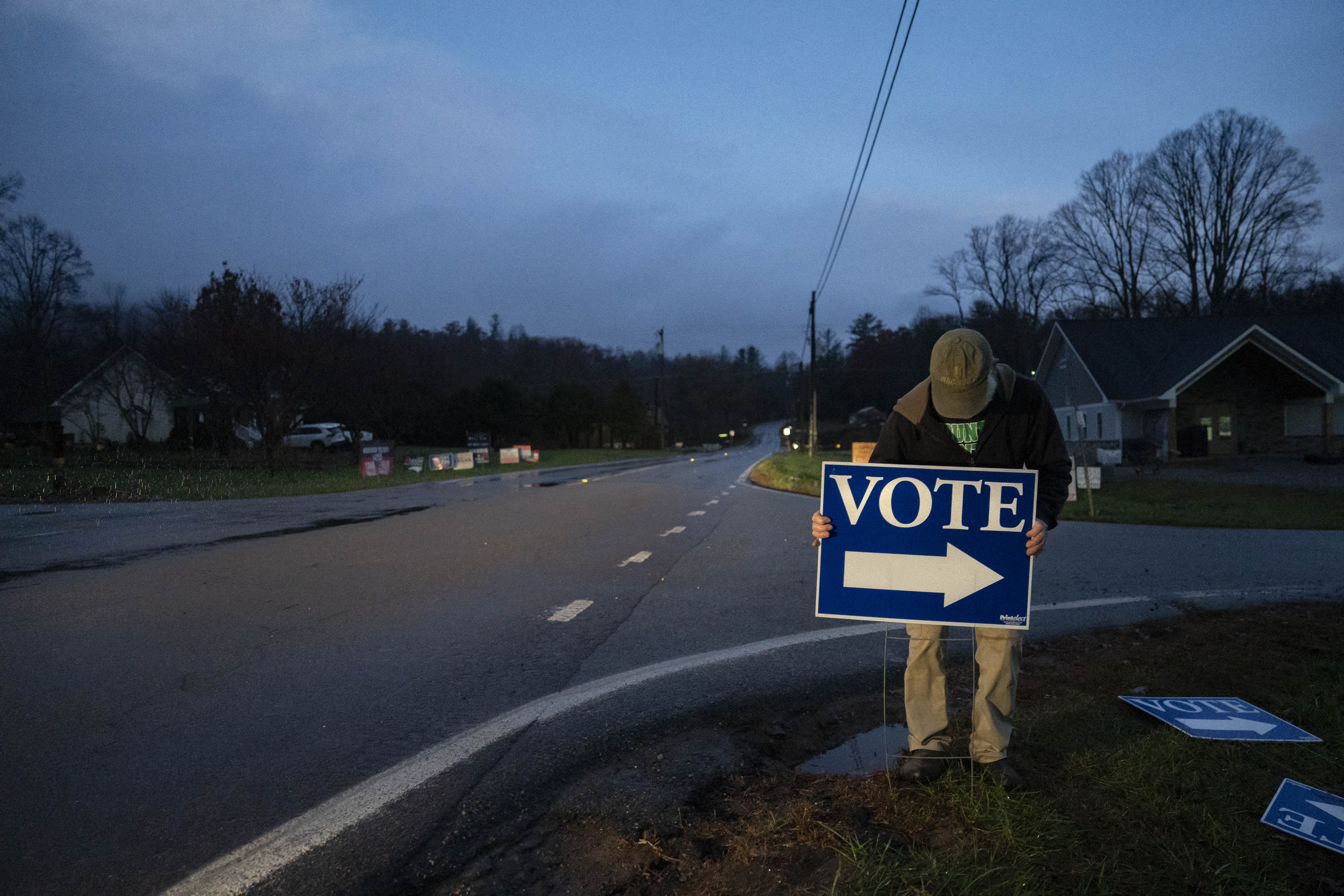 A worker places a sign outside a polling station before polls open Burnsville, North Carolina, on Election Day, November 5, 2024.