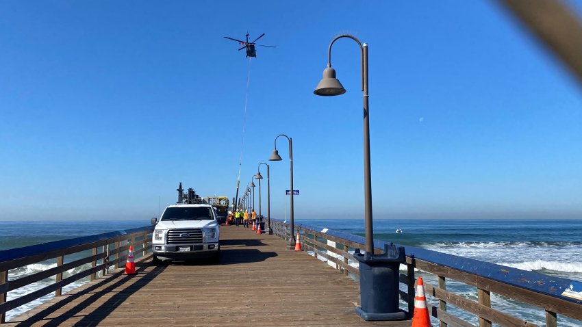 A helicopter bringing in one of the replacement pylons for the Imperial Beach Pier