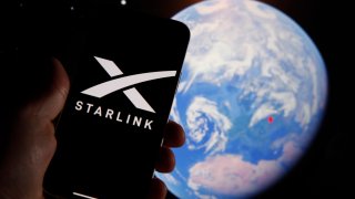 The Starlink logo is seen on a mobile device with an grahpic illustration of planet Earth in this illustration photo in Warsaw, Poland on 21 September, 2022.